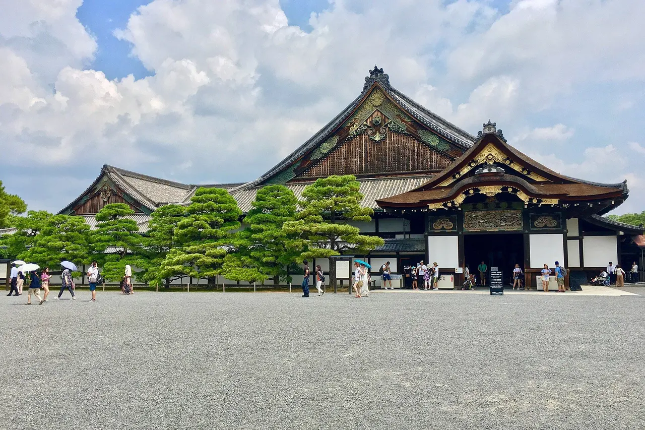 The Ninomaru Palace at Nijo Castle, a long timber palace with an ornate gabled entrance behind a row of clipped pines